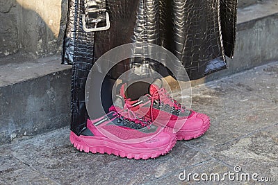 Woman with pink Moncler sneakers and black leather trench coat before MSGM fashion show, Milan Editorial Stock Photo