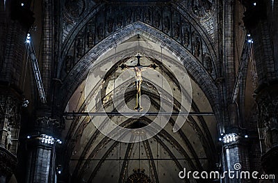 Statue of crucified Jesus Christ inside Milan Cathedral. Holy cross in interior of dark Catholic church, view of crucifix in altar Editorial Stock Photo