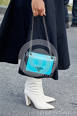 Woman with blue leather Prada bag with studs and white boots before Prada fashion show, Milan Editorial Stock Photo