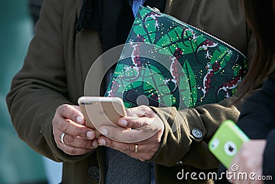 Man with green Furla bag with geckos decoration and iPhone before Emporio Armani fashion show, Milan Fashion Editorial Stock Photo