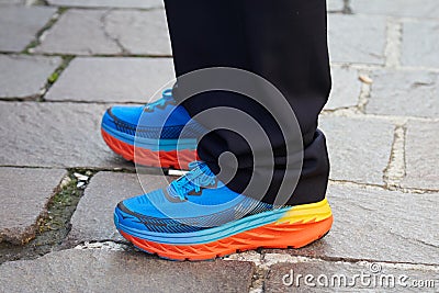 Man with Hoka One Bondi 5 shoes in blue, orange and yellow colors before MSGM fashion show, Milan Fashion Week Editorial Stock Photo