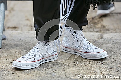 Man with white JW Anderson Converse shoes and black Adidas trousers before Fendi fashion show, Milan Fashion Editorial Stock Photo