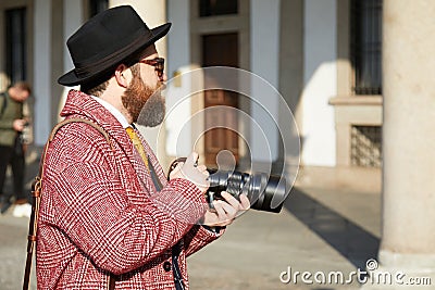 Photographer with red coat and black hat before MSGM fashion show, Milan Fashion Week street style on January Editorial Stock Photo