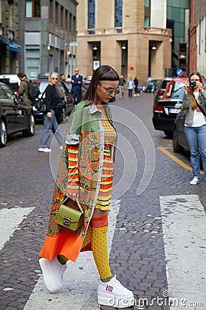 Woman with orange, green, yellow clothing and white wedge heel shoes before Antonio Marras fashion show, Editorial Stock Photo