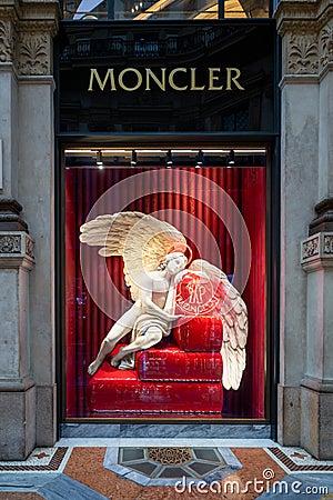 Moncler shop in Galleria Vittorio Emanuele II, Milan, beautiful window in Pre-Christmas time decorated with angel and red curtain. Editorial Stock Photo