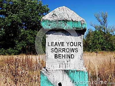 Milestone with sign Leave your sorrows behind. Stock Photo