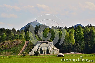 Military aircraft concrete shelter with castle on hill top in background Stock Photo