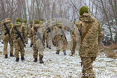 The military in camouflage with Kalashnikov assault rifles, behind their backs, go forward to attack the enemy in winter Editorial Stock Photo