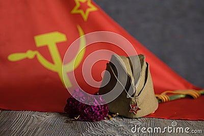Military cap, carnations, Saint George ribbon on a wooden surface Stock Photo