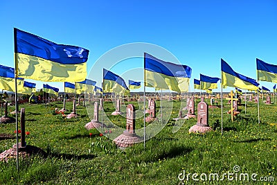 Military cemetery where soldiers who died in Russian war against Ukraine are buried. State Ukrainian flag flutter over graves and Editorial Stock Photo