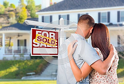 Military Couple Looking At House with Sold For Sale Realty Sign Stock Photo