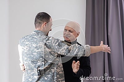 Military father hugs his son when they are reunited after a mission Stock Photo