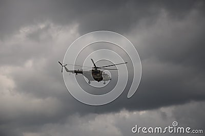 A military helicopter in the sky among gray clouds. Editorial Stock Photo