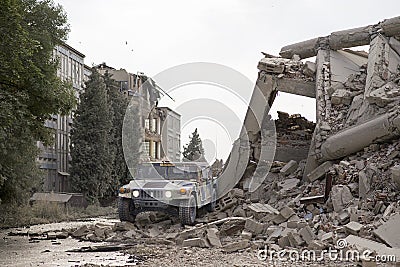 Military hummer in the middle of city ruins, collapsed houses Stock Photo