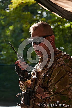 A military major employs a Motorola radio for seamless communication with his fellow soldiers during a tactical Stock Photo