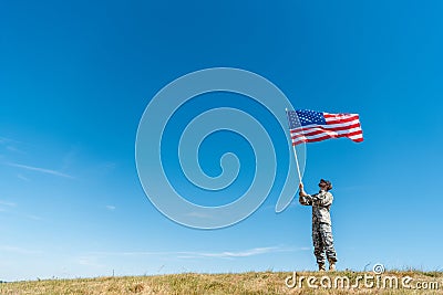 Military man in uniform looking at american flag with stars and stripes Stock Photo