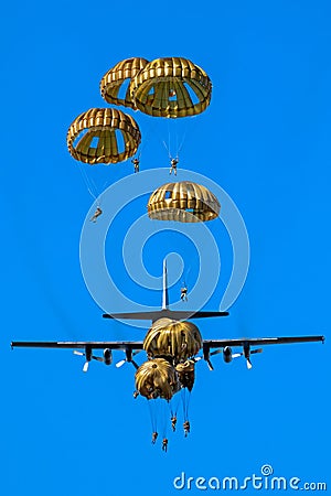 Military parachutist paratroopers parachute jumping out of a air force planes on a clear blue sky day Stock Photo