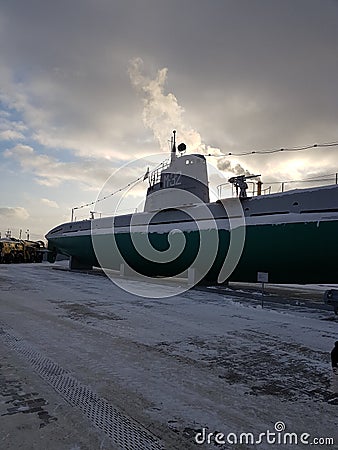 Military submarine in winter. Image of green machinery on a white, fluffy snow background. Editorial Stock Photo