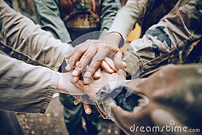 Military, team work or hands in a huddle for a mission, strategy or motivation on a paintball battlefield. Goals Stock Photo
