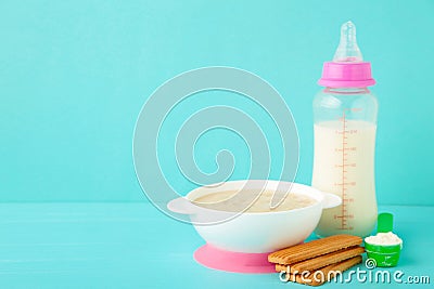 Milk and bowl with porridge for baby on blue background Stock Photo