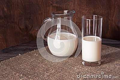 Milk in a glass and a glass jug on a wooden table Stock Photo