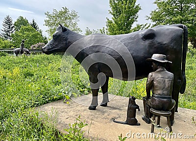 Milking a cow with a cat drinking milk Frederik Meijer Gardens & Sculpture Park Editorial Stock Photo