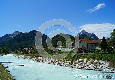 Milky turquoise mountain river running trough the village Mittenwald. Stock Photo