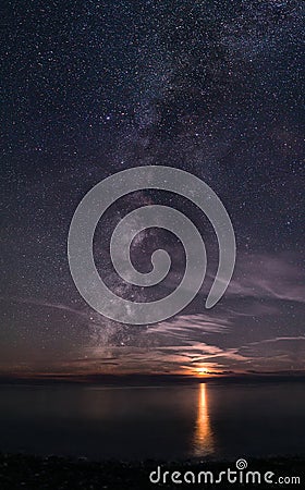 The Milky Way rising out of the sea, next to a setting Moon Stock Photo