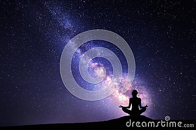 Milky Way and silhouette of a woman practicing yoga. Stock Photo