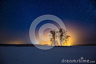 Milky way and starry sky over winter landscape and distant village Stock Photo