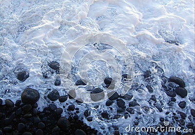 A milky white tide breaking on the rocky shore Stock Photo