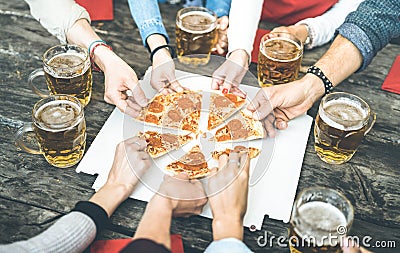 Millenial friends group drinking beer and sharing pizza slices at bar restaurant - Friendship concept with young people having fun Stock Photo