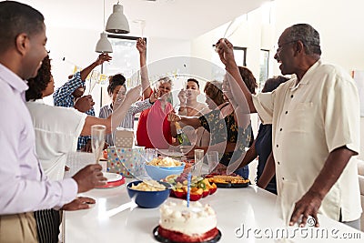 Millennial African American woman pouring champagne during a three generation family celebration at home Stock Photo