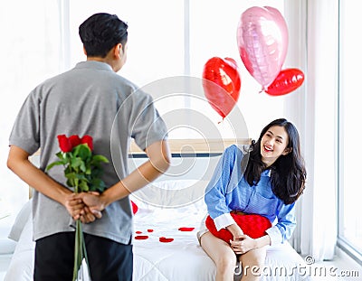 Millennial Asian young romantic lover couple unrecognizable male boyfriend holding red roses bouquet surprising female girlfriend Stock Photo