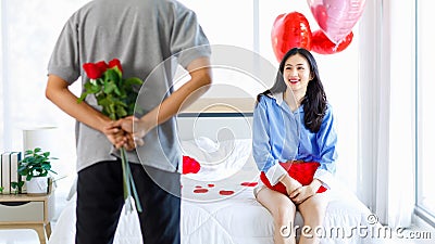 Millennial Asian young romantic lover couple unrecognizable male boyfriend holding red roses bouquet surprising female girlfriend Stock Photo
