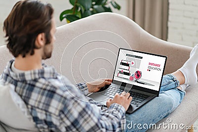 Millennial caucasian guy sits on sofa, using distance education software Stock Photo