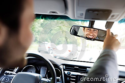 Millennial caucasian guy in suit with hands on steering wheel, configures mirror Stock Photo