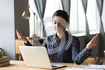 Millennial ethnic woman meditate at workplace at home Stock Photo