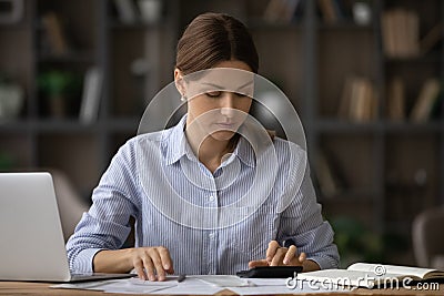 Millennial female social worker counting subsidy rates at office workplace Stock Photo