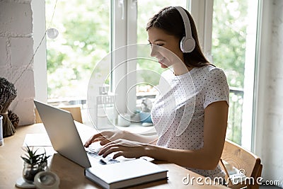 Millennial female studying working online using laptop and wireless headphones Stock Photo