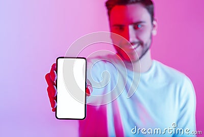 Millennial guy holds touchscreen phone in hand with blank screen in neon light Stock Photo