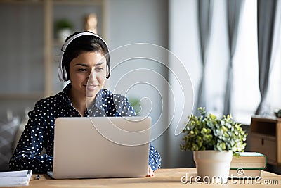 Millennial Indian girl in headphones using laptop at home Stock Photo