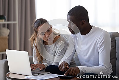 Millennial multiracial married couple calculating monthly family budget. Stock Photo