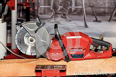 A Milwaukee electric cutter with a diamond wheel rests on a wooden beam. 16.2.222. Kyiv. Ukraine Editorial Stock Photo