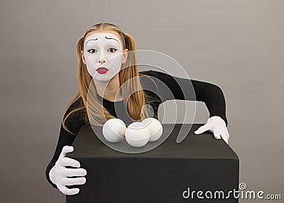 Mime artist near black cube with juggling balls. Circus clown woman Stock Photo