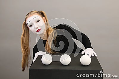 Mime artist near black cube with juggling balls. Circus clown woman Stock Photo