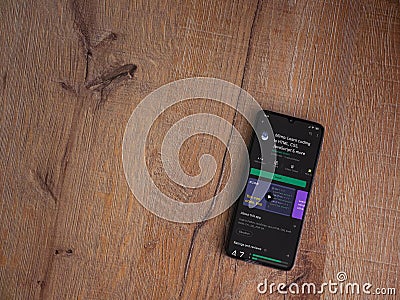 Mimo - Learning coding app play store page on the display of a black mobile smartphone on wooden background Editorial Stock Photo