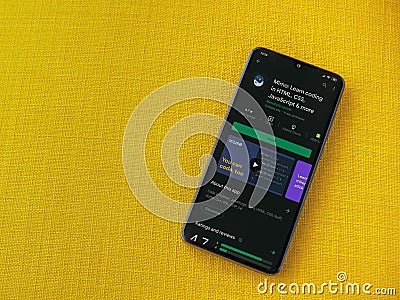 Mimo - Learning coding app play store page on the display of a black mobile smartphone on a yellow fabric background Editorial Stock Photo