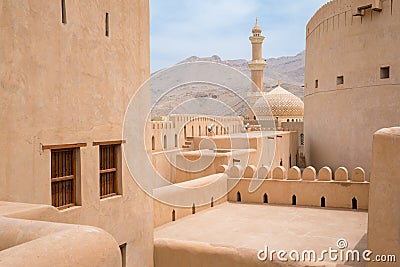 Minaret, dome and walls of medievel arabian fort of Nizwa, Oman. Hot day in arabian desert city. Middle east military Stock Photo