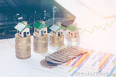 Minature houses resting on graph sheet coin stacks concept for property ladder, Stock Photo